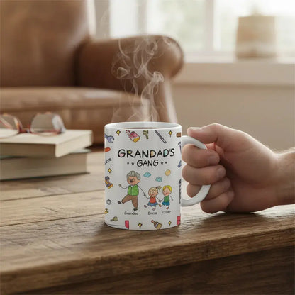 Hand holding a Personalized dad mug with cute grandchildren characters on a wooden table.