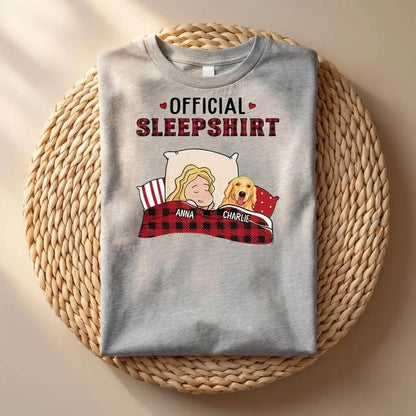 Folded gray sleepshirt with cartoon design of a girl and dog on a woven mat
