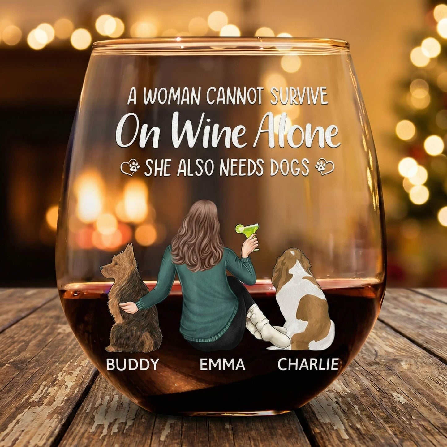Personalized wine glasses with a design of a woman and three dogs, text 'A woman cannot survive on wine alone. She also needs dogs.'