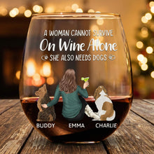 Personalized wine glasses with a design of a woman and three dogs, text 'A woman cannot survive on wine alone. She also needs dogs.'