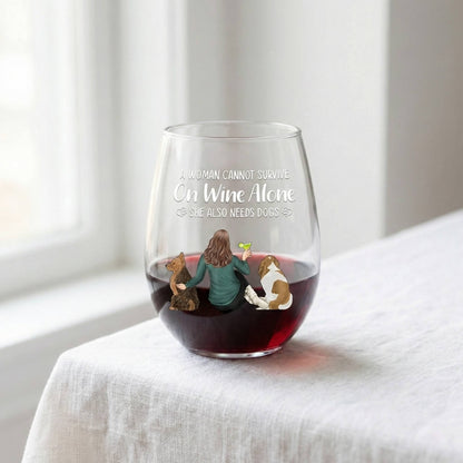 Personalized Stemless wine glass with a design of a woman and two dogs, filled with red wine, on a white surface.